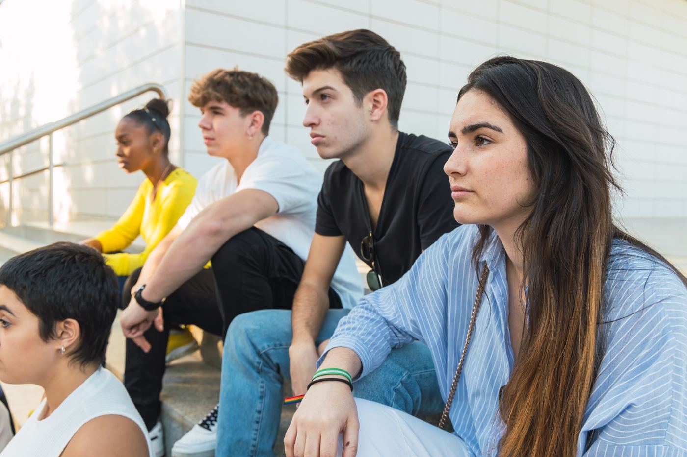 A group of teenagers and young adults sitting together on steps outside, in conversation